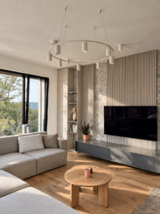 Obývačka s lamelovou TV stenou, rohovou pohovkou a lustrom, Penthouse 143 m² Praha – Dejvice